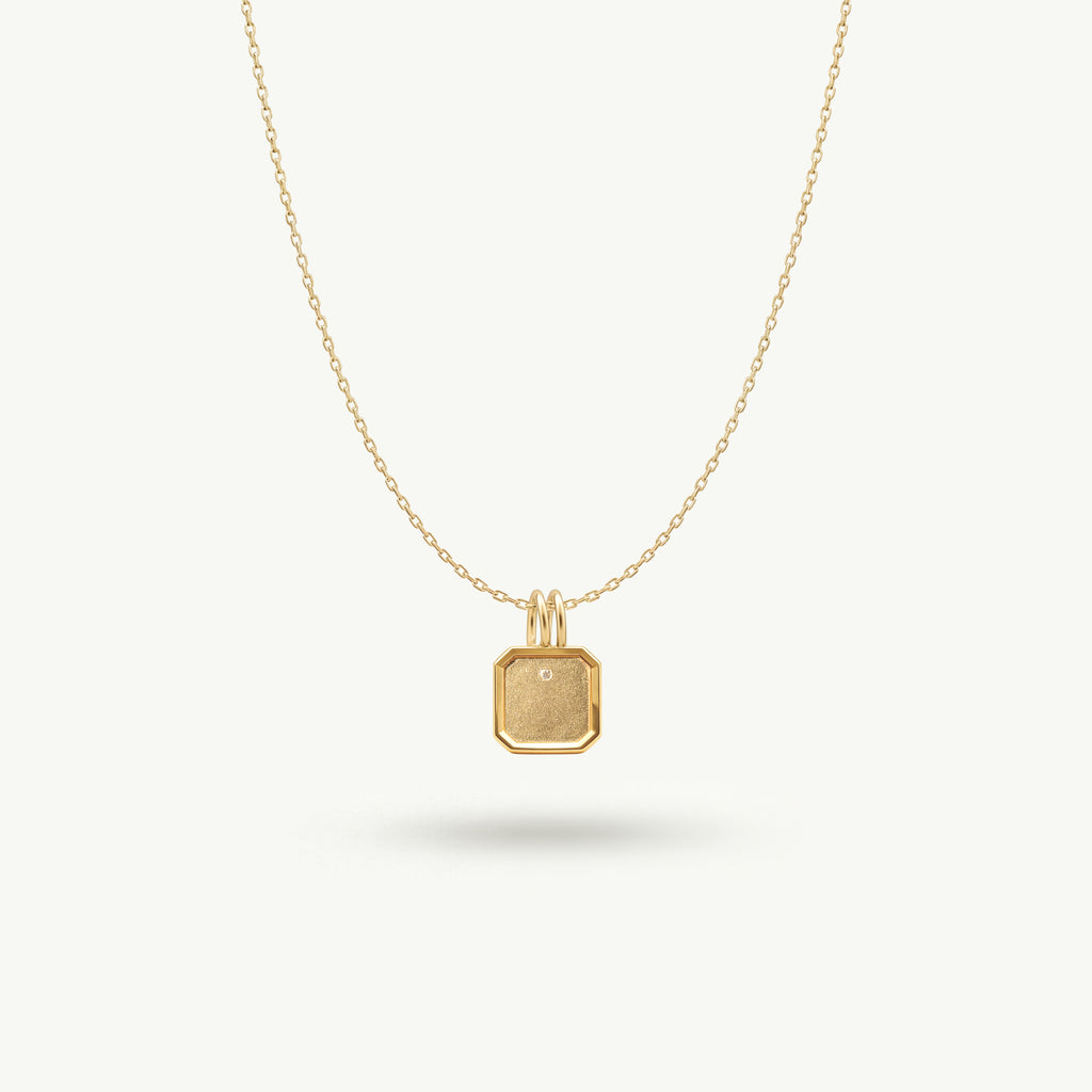 14k solid yellow gold Bria pendant necklace with a textured sandblast finish and a single inset diamond, showcasing a minimal and intentionally restrained design.