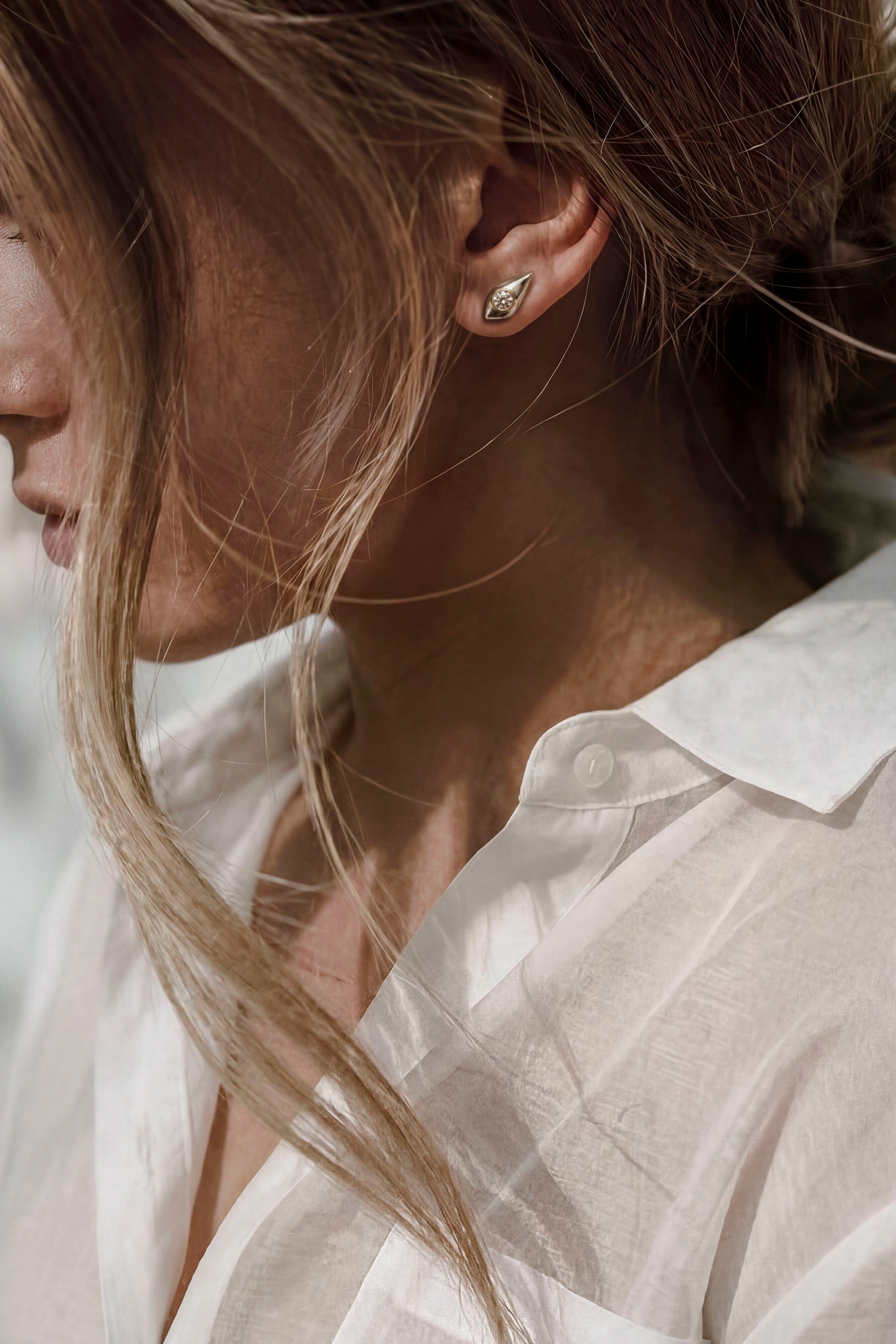 Iris convertible earrings in sterling silver with white sapphire detail, worn as architectural stud earrings with a white button-down shirt.
