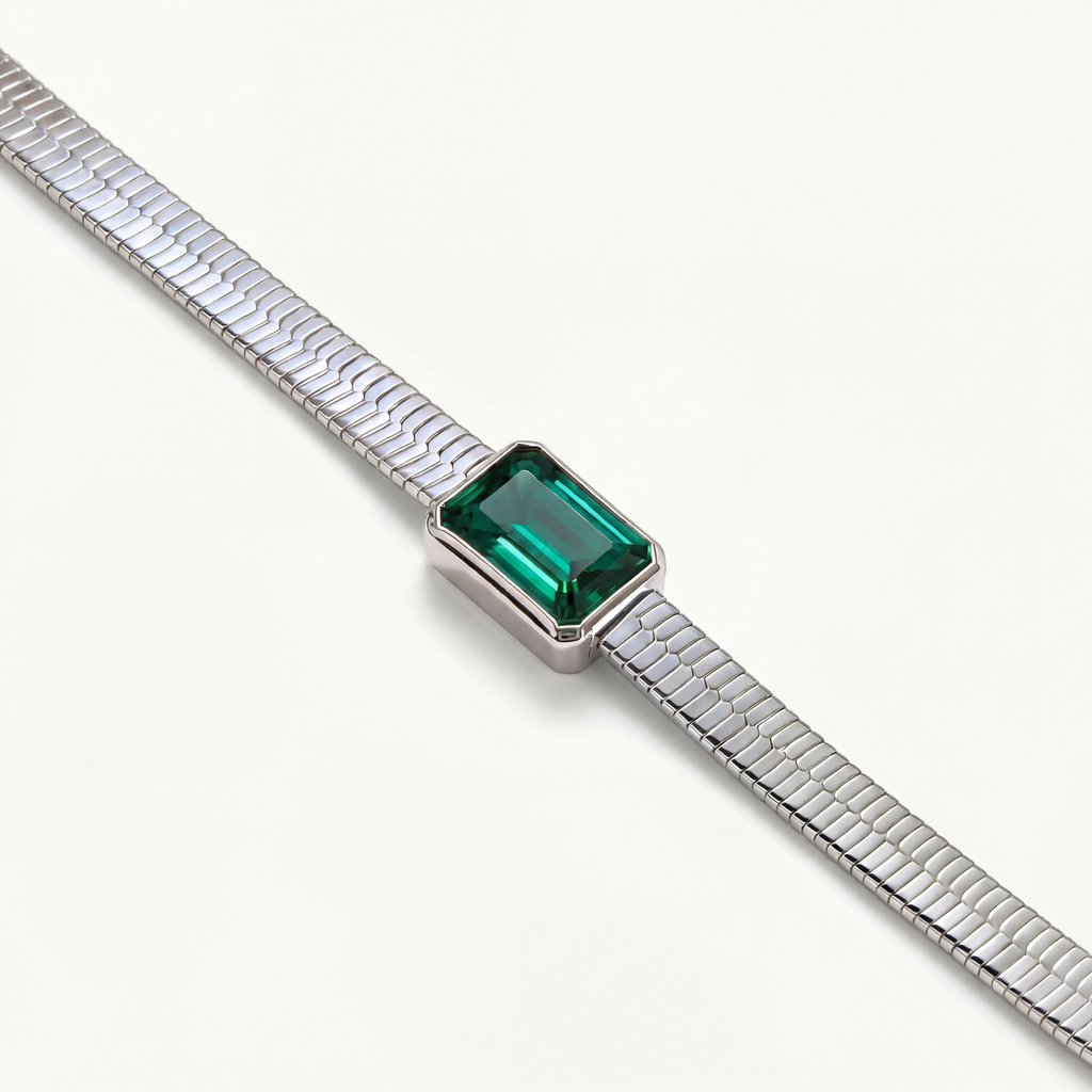 Close-up of the Yorke necklace highlighting the precise emerald cut green emerald and the fluid, architectural form of the herringbone chain.